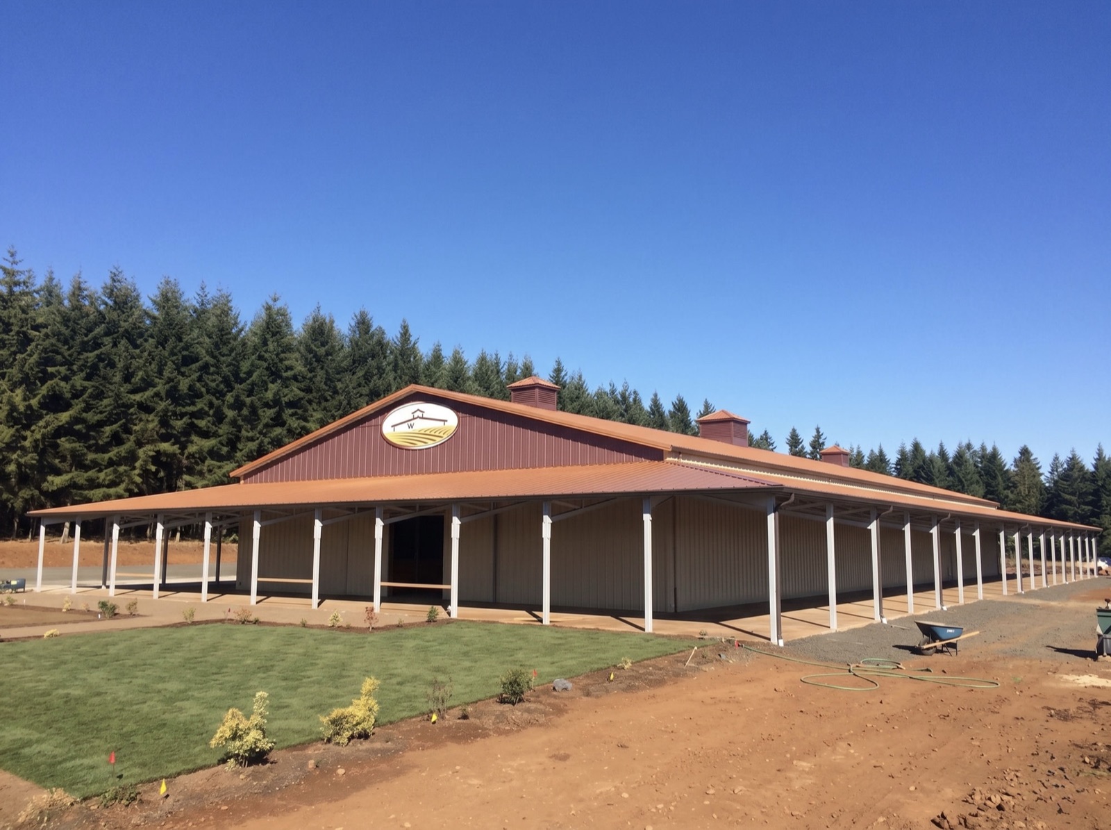Long commercial post-frame building with a wraparound covered porch and copper-toned metal roof, built by Miner Pole Buildings