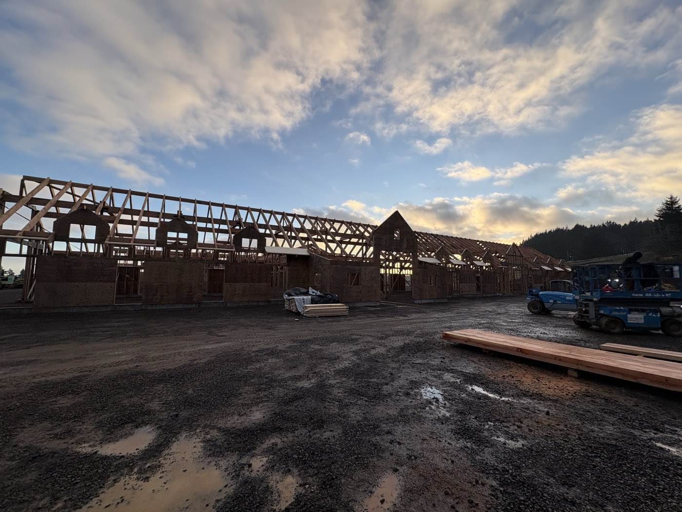 Post-frame stall barn mid-framing at dawn on a Yamhill County, Oregon jobsite