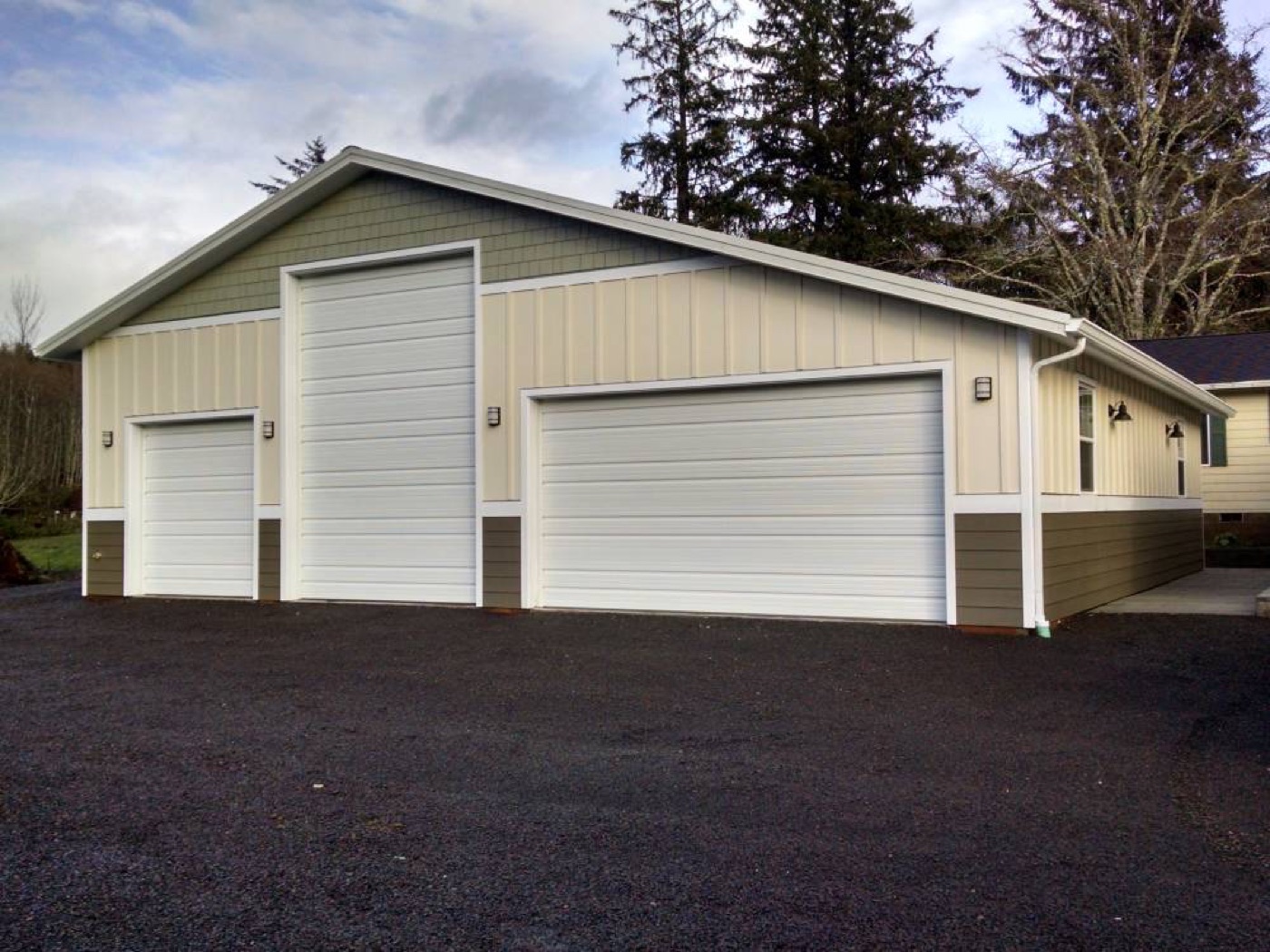Tan and olive three-bay garage with white overhead doors, built by Miner Pole Buildings