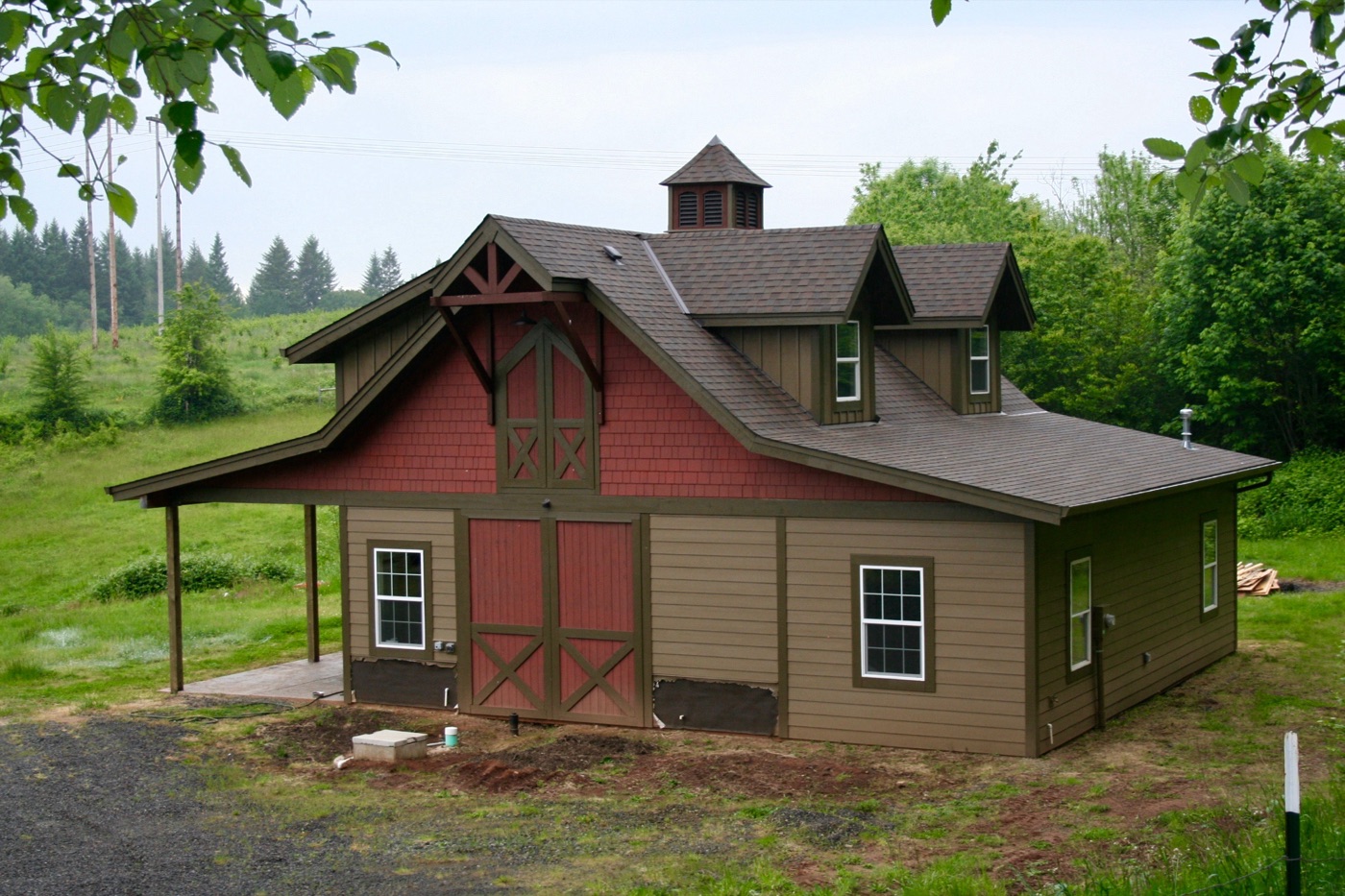 Red monitor barn with a cupola in a green rural setting, built by Miner Pole Buildings