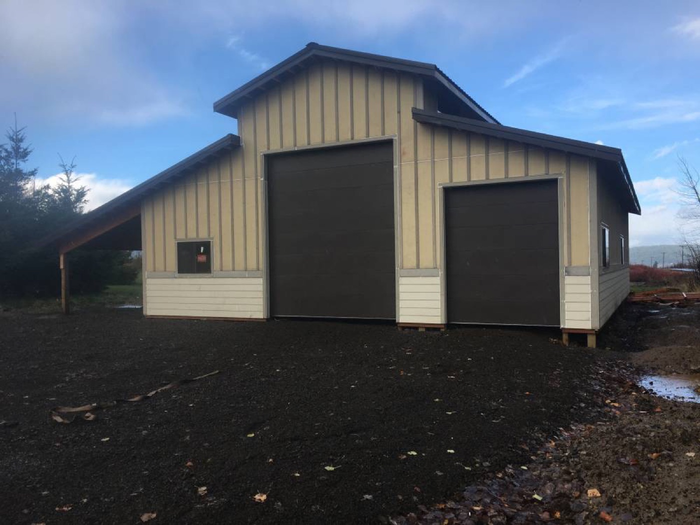 Tan monitor-style barn with dark doors and a raised center, built by Miner Pole Buildings
