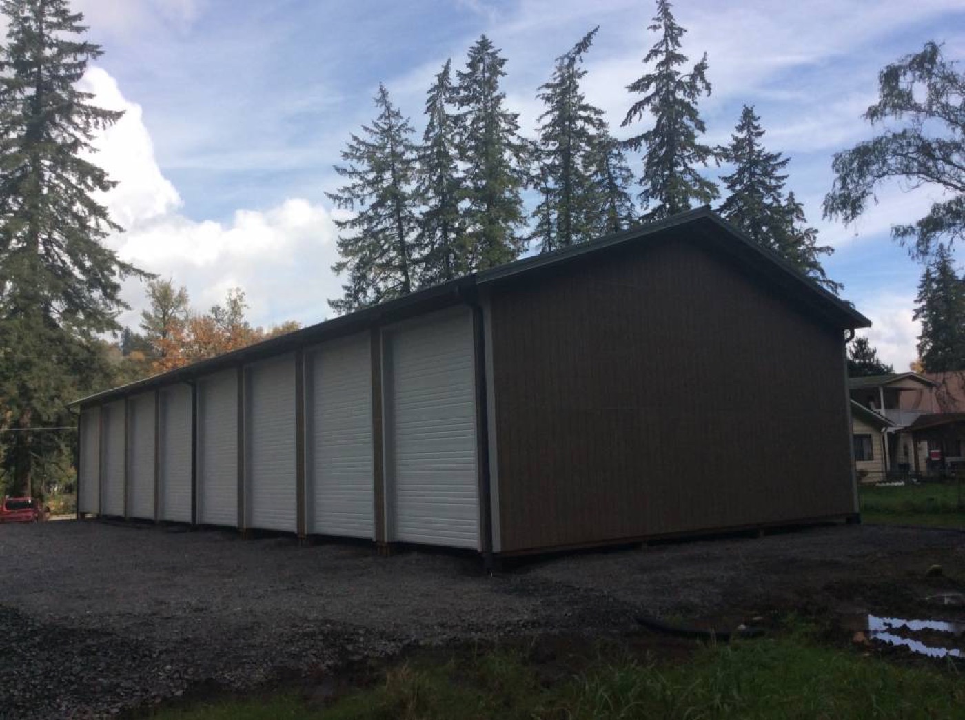Long brown storage building with white roll-up doors, built by Miner Pole Buildings