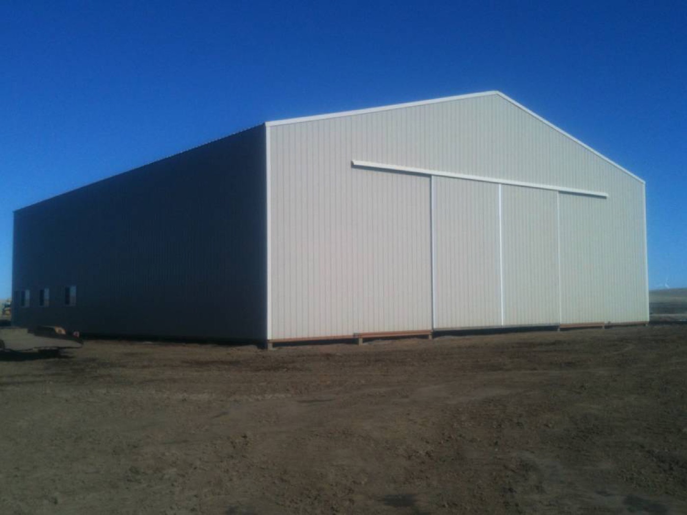 Gray and tan agricultural barn with large sliding doors, built by Miner Pole Buildings