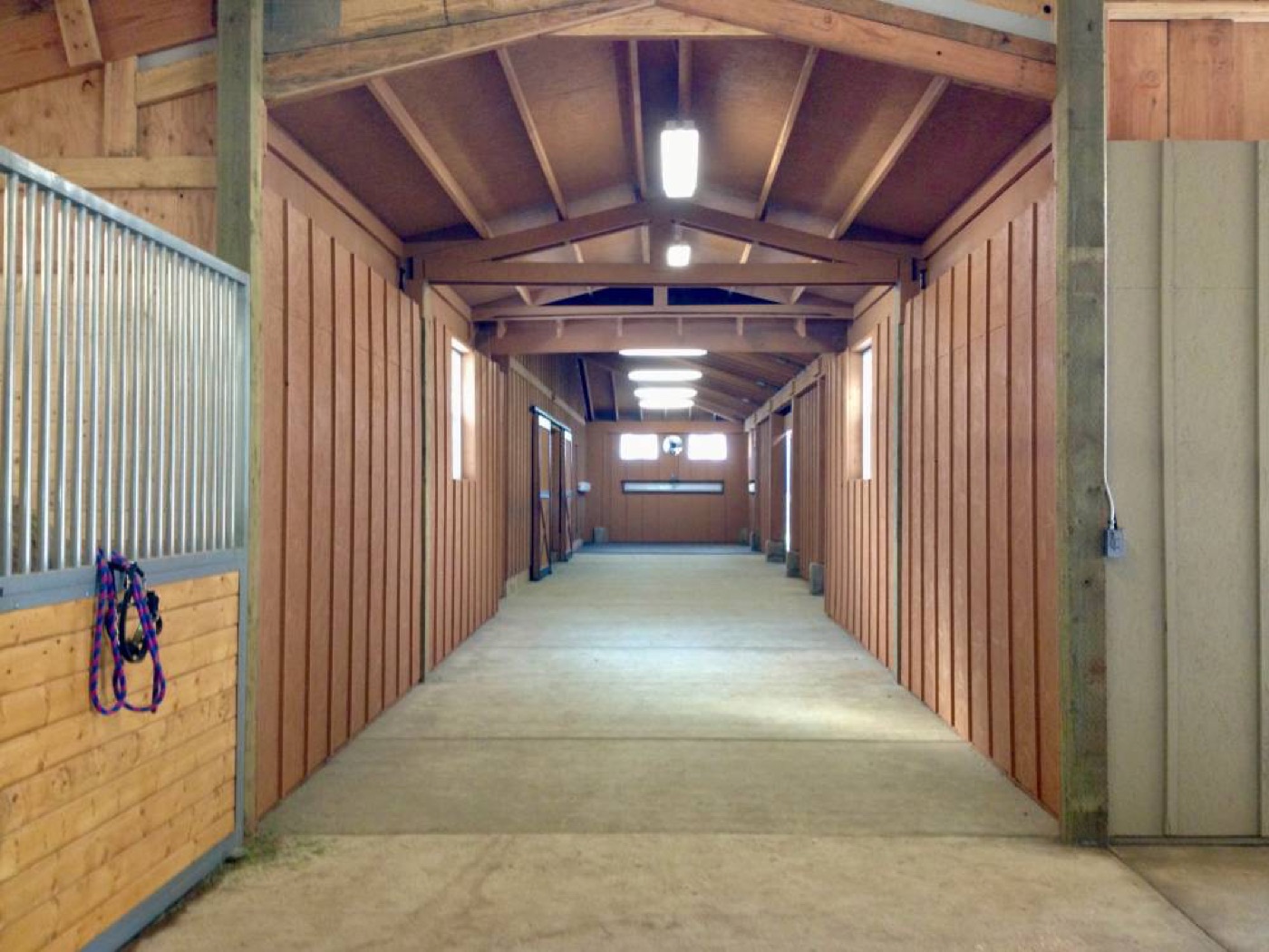 Interior of a wood stable aisle with exposed trusses, built by Miner Pole Buildings