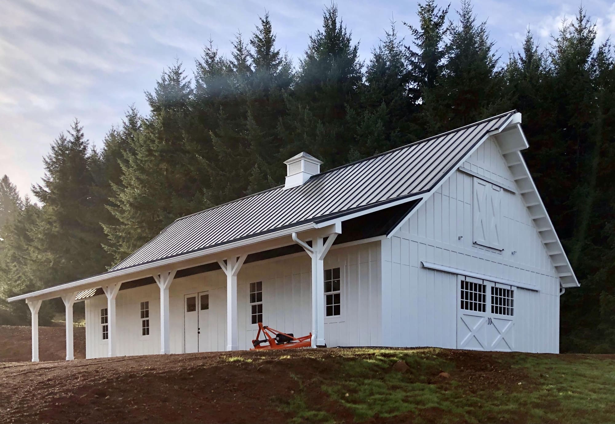 White board-and-batten pole barn with an open lean-to and standing-seam metal roof, built by Miner Pole Buildings